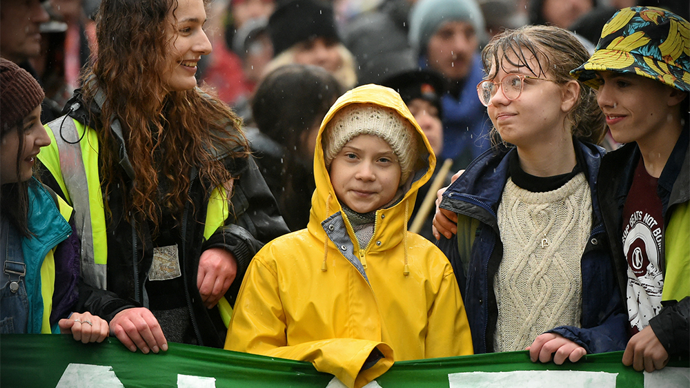Greta Thunberg i sin gula regnrock, omgiven av andra ungdomar i samband med en skostrejk i Bristol den 28 februari 2020