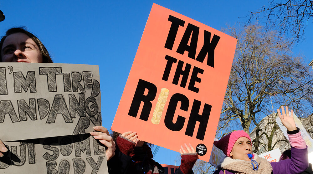 Demonstranter protesterar i London 2020 med skyltar "Tax the rich".