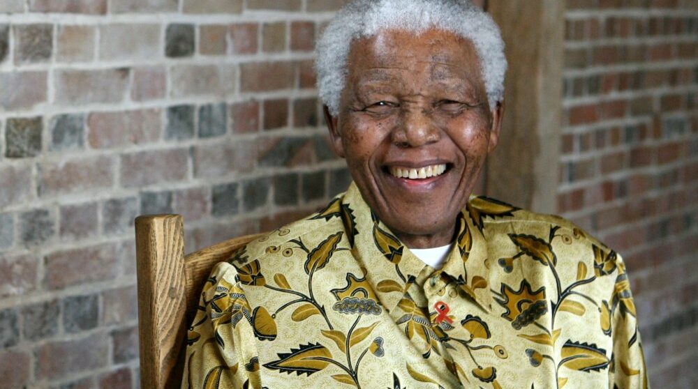 Bild på en glad Nelson Mandela i gul skjorta