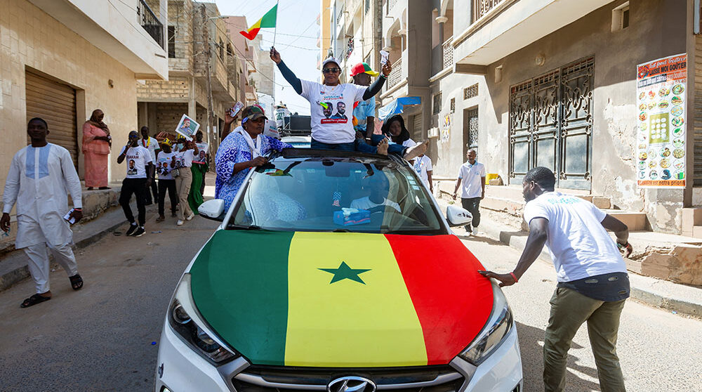Anhängare till Bassirou Diomaye Faye firar segern på bilden en bil meed flagga och jublande människor.