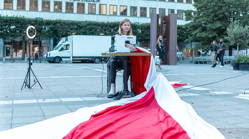 Kvinna som syr belarus flagga på ett torg Stockholm .